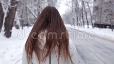 一个年轻的女孩在寒冷的冬天为相机摆姿势。 寒冷的雪