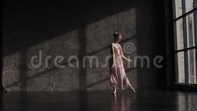 优雅的芭蕾舞女演员穿着一件飘逸的长裙，在演播室的黑暗背景下翩翩起舞