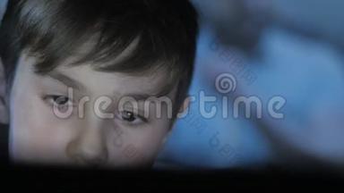 儿童在游戏机上玩电子游戏的特写镜头。 游戏的投影在脸上和墙上。 双人