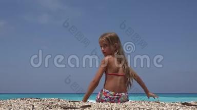 在夕阳下的沙滩上玩耍的孩子，微笑的女孩在海水中扔小石子
