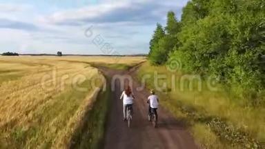 女孩和一个男人骑自行车沿着麦田。 和<strong>家人一起</strong>骑自行车旅行。 从高处<strong>看</strong>美丽的风景