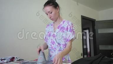女士在家洗衣服后用熨<strong>斗</strong>在熨衣板上熨<strong>烫</strong>衣服。