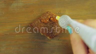 一只手拿着一管烹饪涂料，在带有黄色油漆的巧克力饼干上画着滑稽的脸。 手工制作。