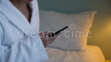 穿白色浴袍的年轻女子坐在酒店的床上