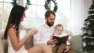 年轻的父亲和他的儿子在看书，而母亲在喝<strong>茶</strong>，听他们说话。 家庭阅读圣诞<strong>故事</strong>