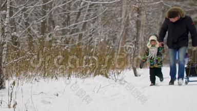 快乐的父亲和一个非常可爱快乐的小男孩，他的儿子在一个雪冬公园里跑步。 微笑的男孩。 有魅力的家庭