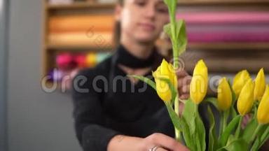 年轻迷人的微笑女人，穿着围裙，在<strong>花店</strong>工作，用<strong>新鲜</strong>的黄色郁金香插花