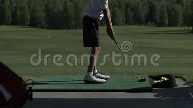 年轻的高尔夫球手在练习场练习高尔夫挥杆，从侧面观看