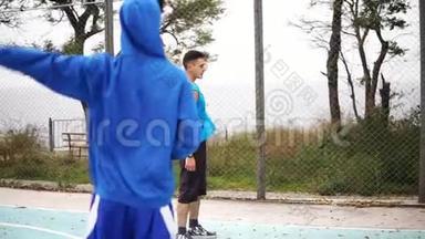 两个年轻的朋友在街上打篮球前热身。 慢镜头