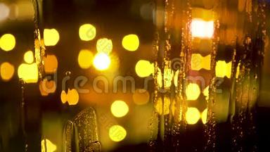 抽象模糊的夜晚城市灯光和雨滴在潮湿的玻璃后面
