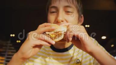 青少年吃快餐。 <strong>快餐厅</strong>里少年咬芝士汉堡的特写镜头。