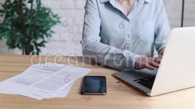 妇女在<strong>办公</strong>室的<strong>办公</strong>桌上使<strong>用笔</strong>记本电脑和智能手机