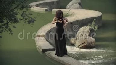 穿裙子的漂亮女孩在户外拉小提琴。 森林中优雅的小提琴手