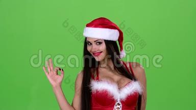 穿着圣诞老人红色西装的女孩眨了眨眼睛，露出了她的手指。绿色屏幕。 关门