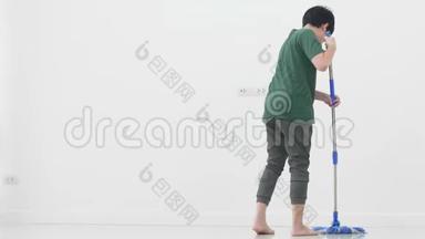 亚洲小男孩帮助家人用拖把打扫房子。