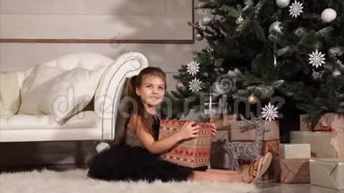 在庆祝活动的晚上，漂亮的小女孩正坐在圣诞树下