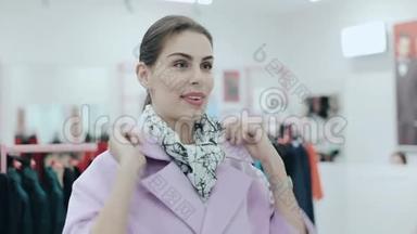 年轻苗条的女士穿着一件外套。 女人在镜子前购物和检查粉红色外套。 风格和风格