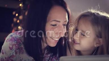 <strong>一家人</strong>的母亲和女儿在躺在地上数字平板电脑上的礼物。 <strong>圣诞节</strong>。