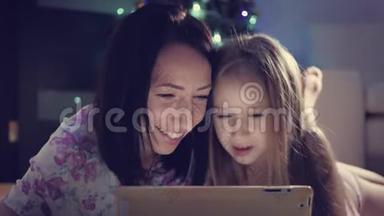 <strong>一家人</strong>的母亲和女儿在躺在地上数字平板电脑上的礼物。 <strong>圣诞节</strong>。