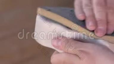 木匠用砂纸打磨一个木制零件. <strong>特写双手</strong>。
