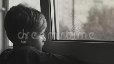孩子悲伤而孤独地透过窗户看。 孩子沮丧的黑<strong>白镜</strong>头