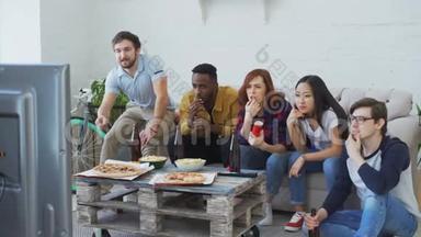 一群在<strong>电视</strong>上<strong>观看</strong>奥运会比赛的年轻朋友一起吃零食和喝啤酒。 其中有些人很高兴