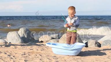 一个小男孩正在海边玩沙子和梨。
