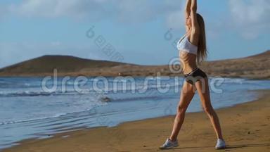 女人伸展腿和腿筋做站立前弯曲瑜伽伸展姿势在海滩上。 健身妇女放松身心