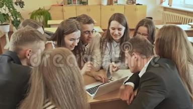 同学们围坐在课桌旁，用笔记本电脑讨论学校的任务。俄罗斯学校。
