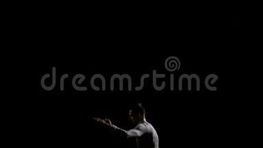 穿着白色衣服的运动员在黑色单音背景的蹦床上表演花样
