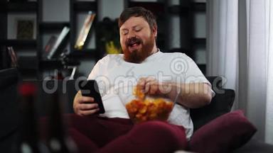 胖子微笑着看着智能手机里的东西，吃着薯片
