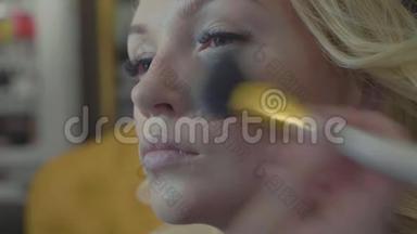 年轻的化妆师把<strong>遮瑕</strong>膏涂在模特`脸上。