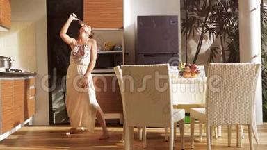快乐的年轻女人在阳光明媚的早晨做早餐时，在厨房里唱歌跳舞很有趣。 3840x2160