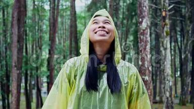 穿黄色雨衣站在雨中的快乐亚洲女人的肖像