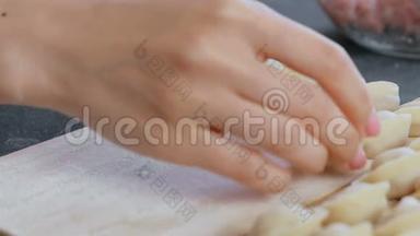 女人用肉馅包饺子，特写的手。 把饺子<strong>放在木板上</strong>。