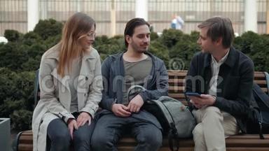 三个惊讶的学生在街上用智能手机查看在线内容，快乐的朋友在街上散步