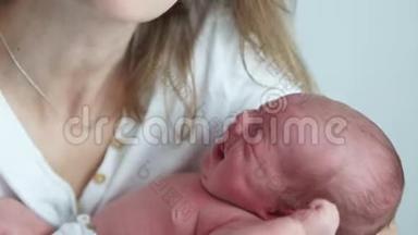 一个两周大的婴儿在他母亲的怀里哭。 新生儿的绞痛。 母亲安抚她哭泣的婴儿