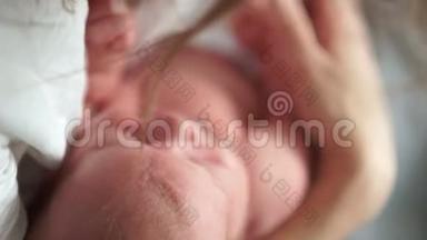 一个新生婴儿睡在母亲的怀里。 母亲节。 母亲轻轻地平静下来，抱着她的孩子。 从一边到另一边摆动