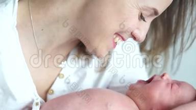 一个新生婴儿在母亲的怀里打哈欠。 <strong>妈妈</strong>在对她的孩子微笑。 <strong>母亲节</strong>
