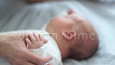 妈妈轻轻地抚摸她新生婴儿的手。 皮肤到皮肤上。 快乐的母亲