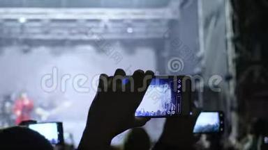 现代科技，手里拿着电话的崇拜者在舞台上欣赏摇滚表演