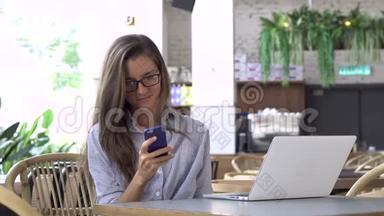 戴眼镜的女人用智能手机，桌上的笔记本电脑