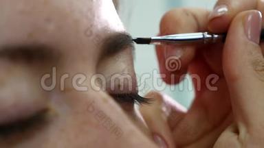 化妆师用刷子`假睫毛模特眉毛的特写镜头