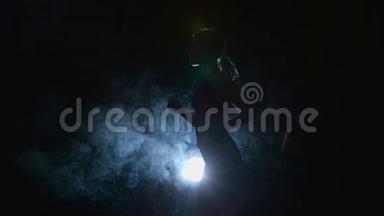 运动员在烟雾中被聚光灯照亮的黑色背景<strong>上轻轻地</strong>奔跑。 剪影。 慢动作