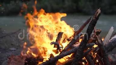 傍晚，熊熊燃烧的篝火熊熊燃烧. 慢动作，180fps.. 火在河底燃烧.. 火花