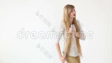 开朗迷人的少女用扫帚唱歌跳舞，就像白色背景上的麦克风。