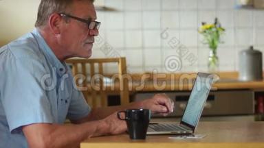 网上购物。 一个养老金领取者在厨房喝茶，并通过互联网支付他的账单。 现代技术