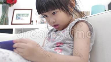 小亚洲女孩在家里微笑<strong>着看着手机</strong>。