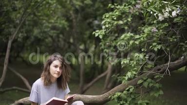 女孩在公园里读一本好书，向下倾斜