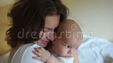 年轻的母亲把孩子抱在卧室里。 一个女人小心翼翼地拥抱一个三个月大的婴儿。 母亲节
